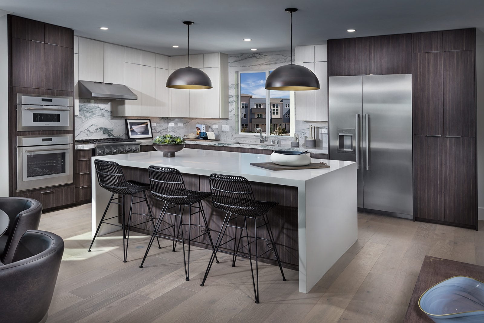 Modern kitchen with brown cabinetry, large marble island, and wood panel flooring.